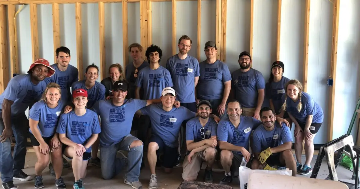 Group of employees in matching blue T-shirts volunteering at a Habitat for Humanity build