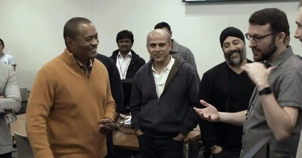Group of men talking and laughing during a hackathon gathering in a conference room
