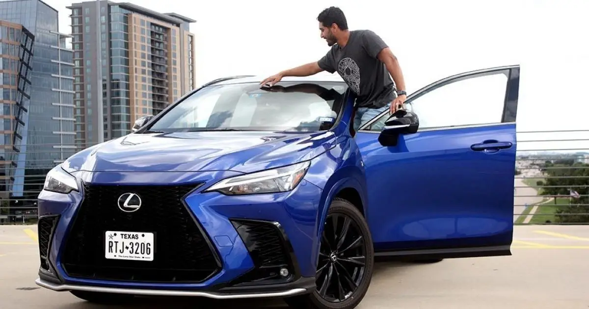 Man leaning on a blue Lexus NX parked on a rooftop with a city skyline behind