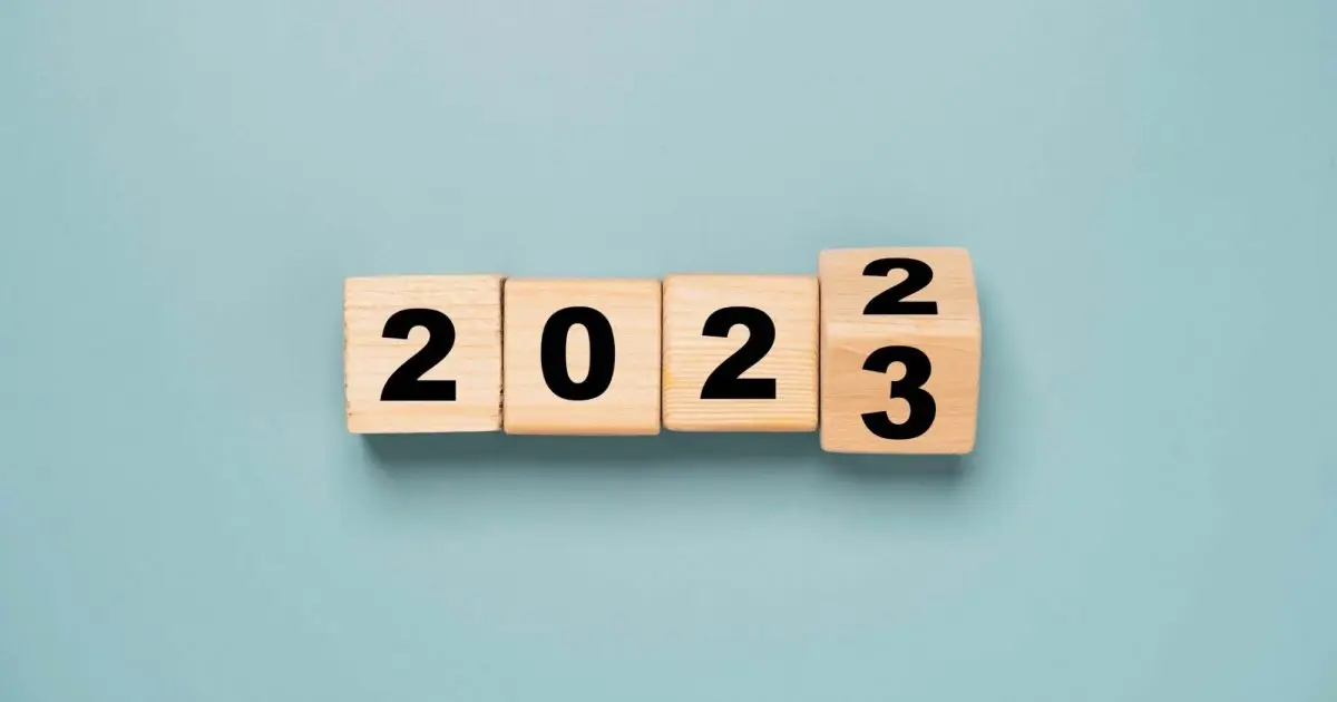 Wooden blocks spelling 2022 flipping to 2023 against a pale blue background