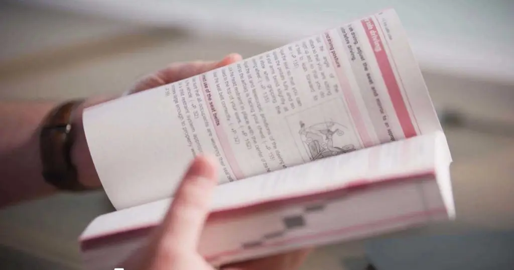 Hands holding an open Toyota owner's manual showing seat and driving posture instructions